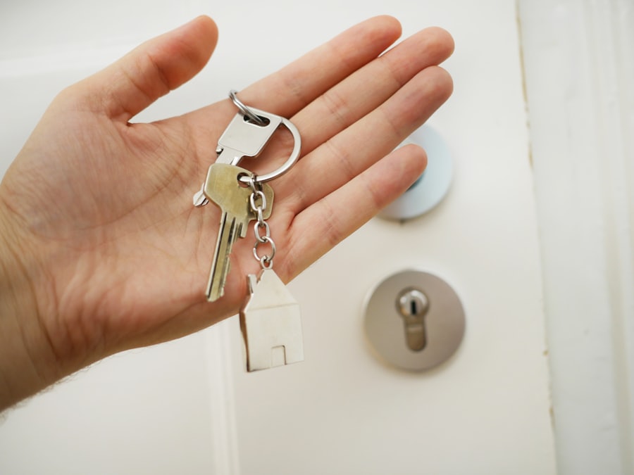 Main tenant un jeu de clés devant une porte d'entrée équipée d'un cylindre